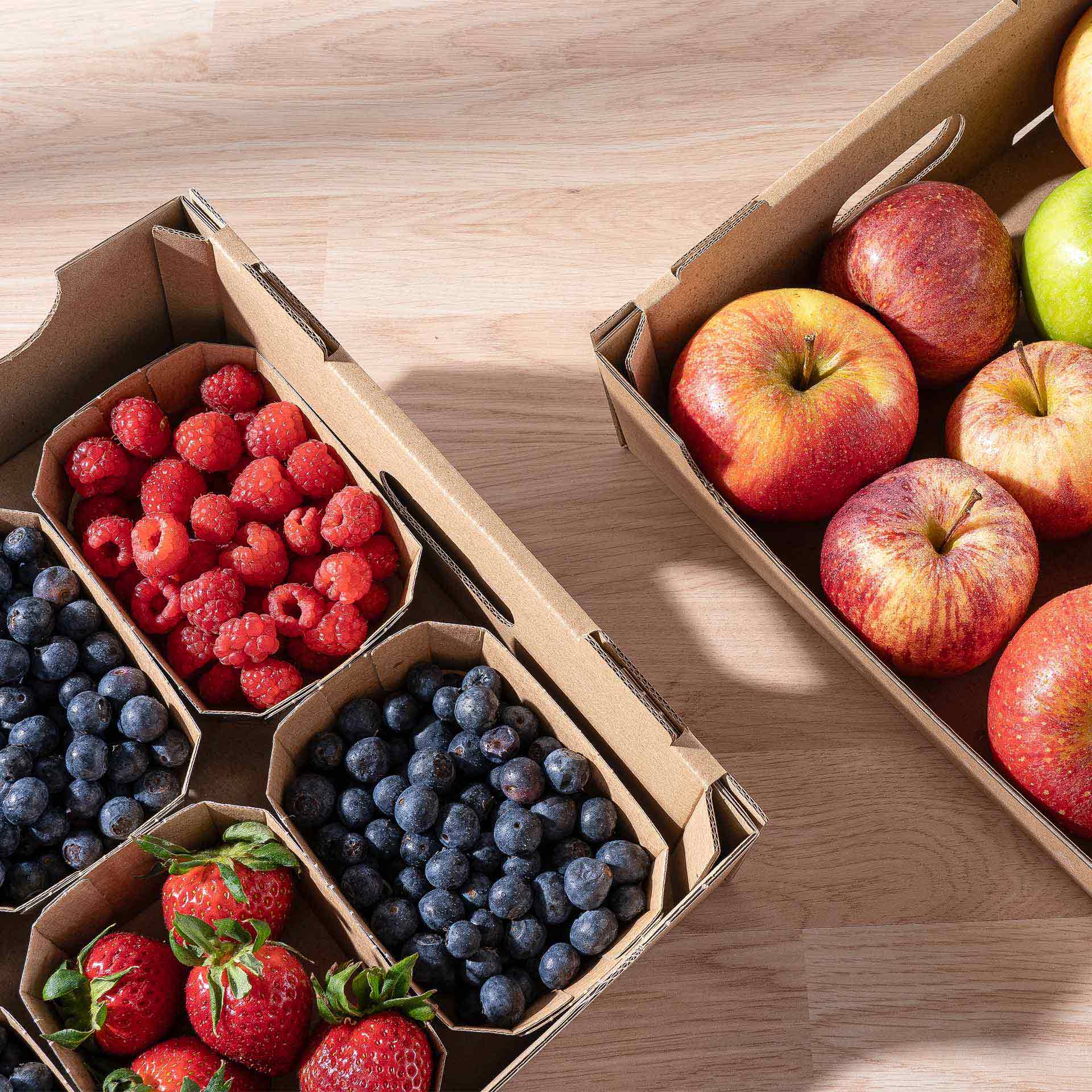 Zwei Steigen gefüllt mit Äpfel und Beeren in der Draufsicht